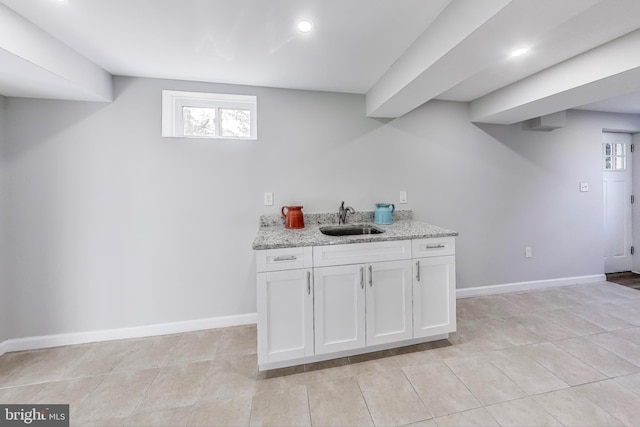 kitchen featuring white cabinets, sink, and light stone counters