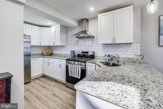 kitchen featuring white cabinetry, stainless steel appliances, and wall chimney range hood