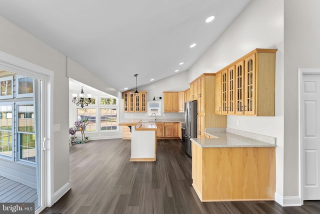 kitchen with dark hardwood / wood-style flooring, stainless steel refrigerator, lofted ceiling, and light stone counters