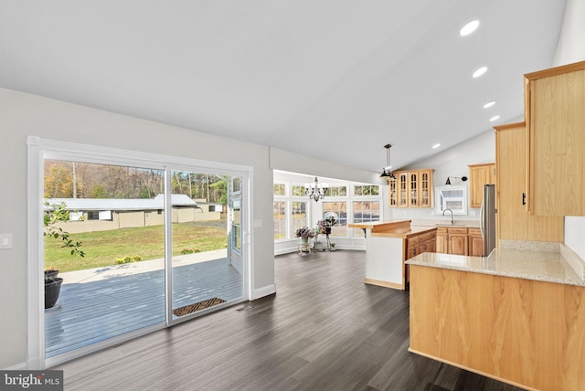 kitchen featuring vaulted ceiling, decorative light fixtures, dark hardwood / wood-style flooring, kitchen peninsula, and stainless steel refrigerator