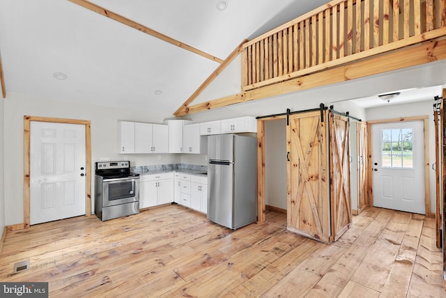 kitchen featuring appliances with stainless steel finishes, light wood-type flooring, a barn door, high vaulted ceiling, and white cabinetry