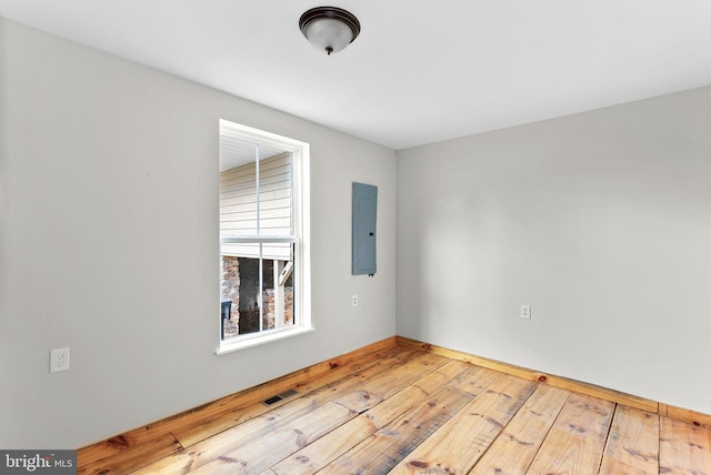 unfurnished room with electric panel and light hardwood / wood-style flooring