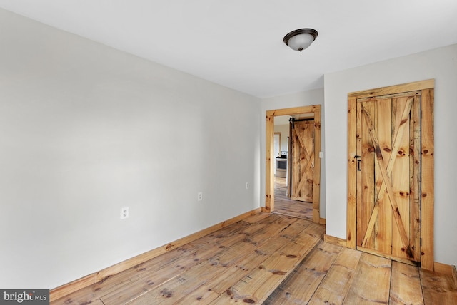 spare room with a barn door and light hardwood / wood-style floors