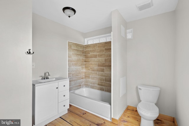 full bathroom with hardwood / wood-style floors, vanity, toilet, and tiled shower / bath