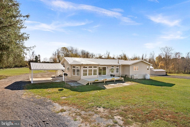 rear view of property with a carport and a yard