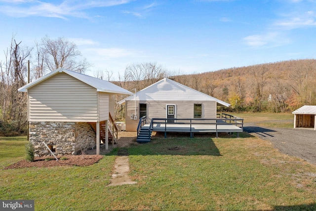 back of house with a deck and a lawn