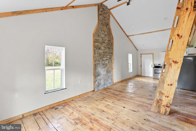 unfurnished living room with beamed ceiling, high vaulted ceiling, and light wood-type flooring