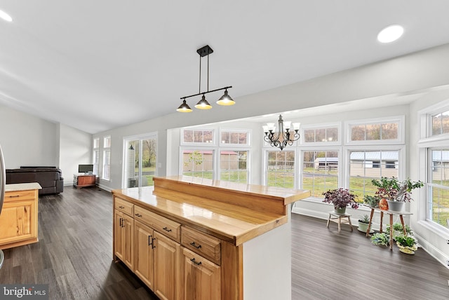 kitchen featuring wood counters, an inviting chandelier, hanging light fixtures, dark hardwood / wood-style floors, and a kitchen island