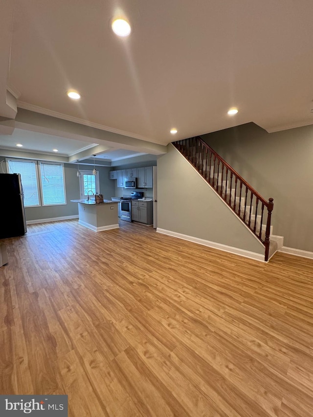 unfurnished living room with light hardwood / wood-style floors and crown molding