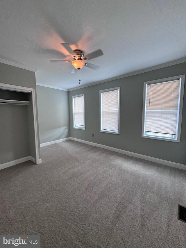 unfurnished bedroom featuring a closet, carpet, ceiling fan, and crown molding