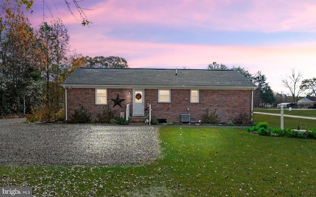 ranch-style home with a yard and central air condition unit