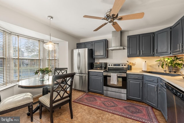 kitchen featuring ceiling fan, sink, wall chimney exhaust hood, hanging light fixtures, and stainless steel appliances