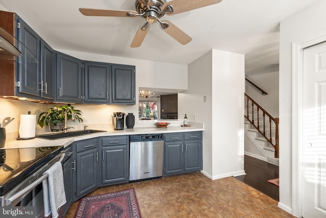 kitchen with tile patterned flooring, appliances with stainless steel finishes, ceiling fan with notable chandelier, and sink