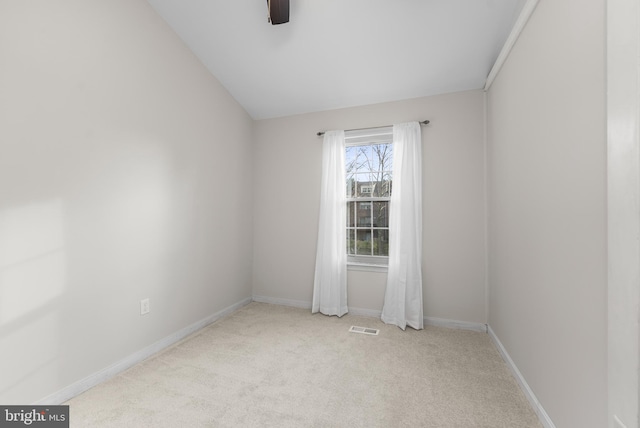 spare room with ceiling fan, light colored carpet, and vaulted ceiling