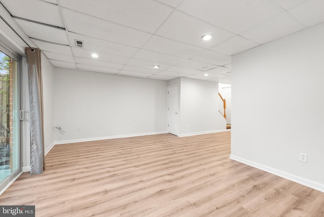 basement with a paneled ceiling and light wood-type flooring