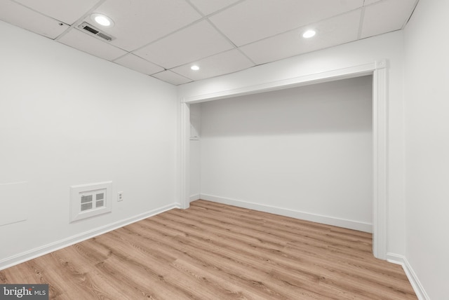 spare room with light hardwood / wood-style flooring and a drop ceiling