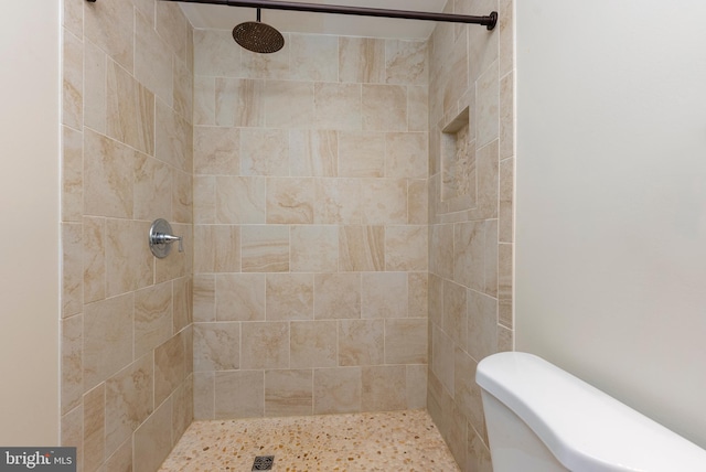 bathroom featuring toilet and a tile shower