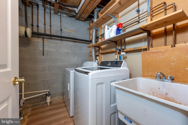 clothes washing area with hardwood / wood-style flooring, sink, and washing machine and clothes dryer