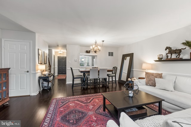 living room with dark hardwood / wood-style flooring and an inviting chandelier