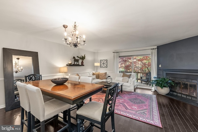 dining area with dark hardwood / wood-style floors and an inviting chandelier