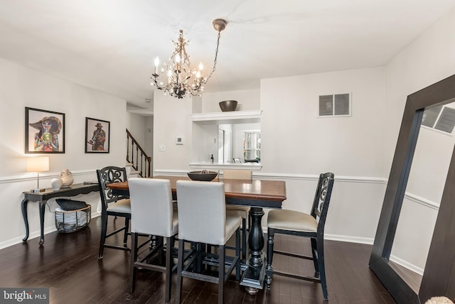 dining area featuring dark wood-type flooring and an inviting chandelier