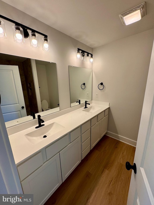 bathroom featuring wood-type flooring, toilet, and vanity