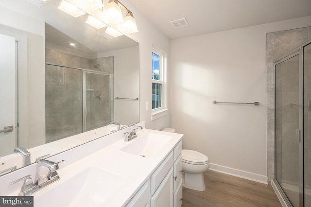 bathroom featuring toilet, vanity, wood-type flooring, and a shower with shower door