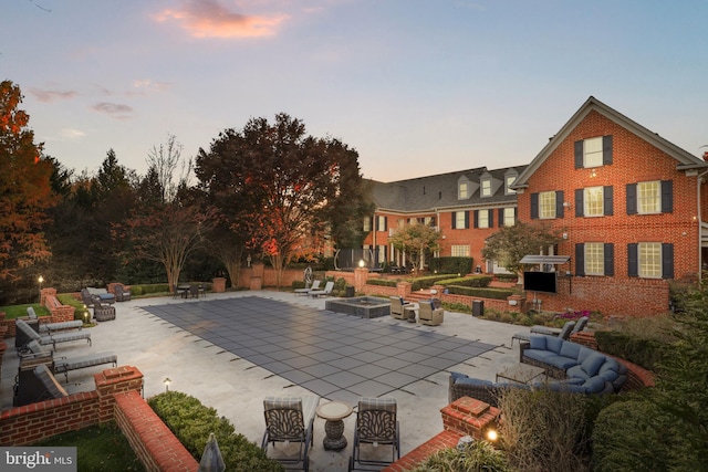 pool at dusk with a patio area and an outdoor fire pit