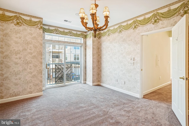 empty room featuring carpet flooring and a chandelier