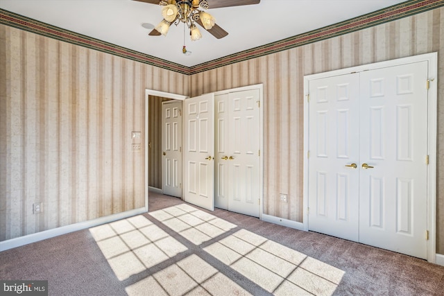 unfurnished bedroom featuring multiple closets, ceiling fan, and carpet floors