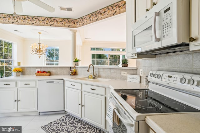 kitchen featuring decorative columns, white appliances, sink, white cabinets, and light tile patterned flooring