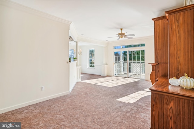 unfurnished living room featuring carpet flooring, ornate columns, crown molding, and ceiling fan