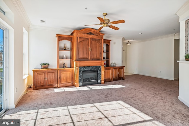 unfurnished living room featuring ceiling fan, ornamental molding, light carpet, and a high end fireplace