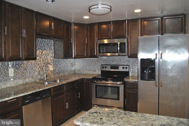 kitchen featuring dark brown cabinets, sink, light tile patterned floors, and stainless steel appliances