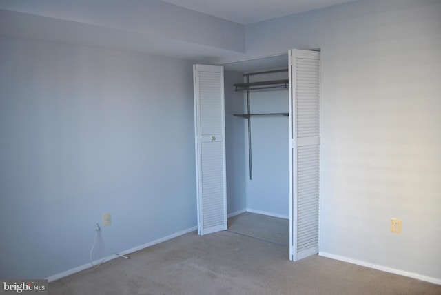 unfurnished bedroom featuring light colored carpet and a closet