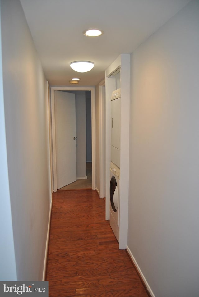 corridor with stacked washer / dryer and dark wood-type flooring