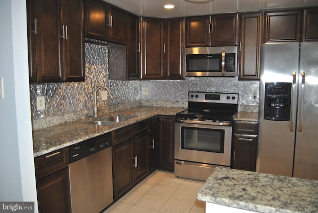 kitchen featuring sink, decorative backsplash, light tile patterned floors, light stone countertops, and appliances with stainless steel finishes