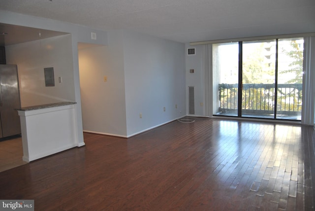 unfurnished living room featuring electric panel, dark wood-type flooring, and a textured ceiling