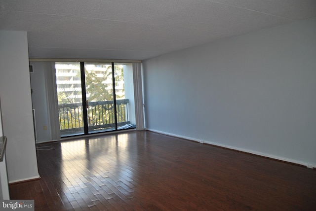 spare room with a textured ceiling and dark hardwood / wood-style flooring