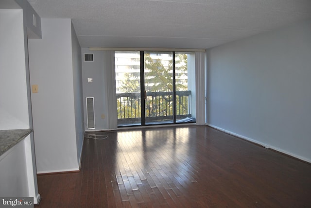 empty room featuring a textured ceiling and dark hardwood / wood-style floors