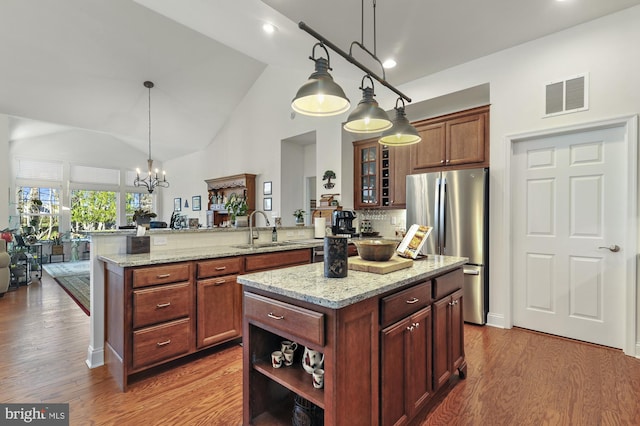 kitchen with stainless steel refrigerator, pendant lighting, kitchen peninsula, and a center island