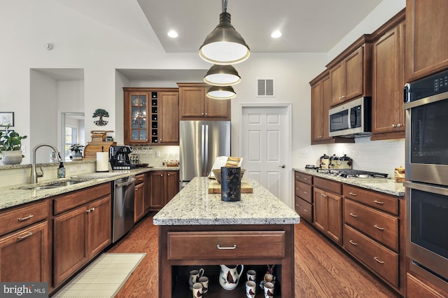 kitchen featuring a kitchen island, appliances with stainless steel finishes, hanging light fixtures, sink, and dark wood-type flooring