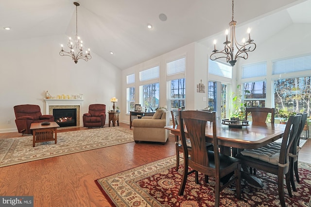 dining area featuring high vaulted ceiling, a chandelier, and wood-type flooring