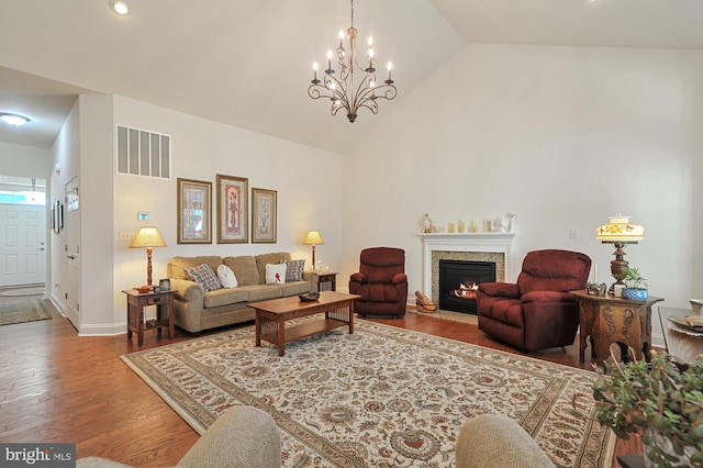 living room featuring wood-type flooring, a chandelier, and high vaulted ceiling