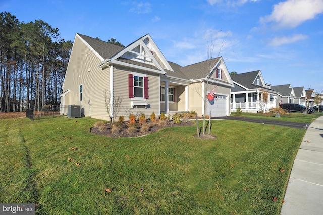 view of front of home with central AC unit, a garage, a front yard, and covered porch