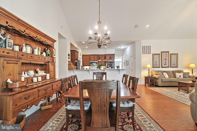 dining area with lofted ceiling, a notable chandelier, and dark hardwood / wood-style floors