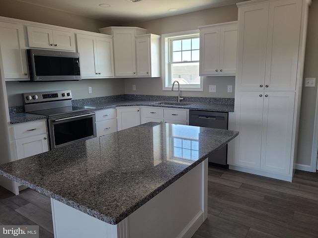 kitchen featuring dark wood-type flooring, a sink, dark stone countertops, appliances with stainless steel finishes, and white cabinets