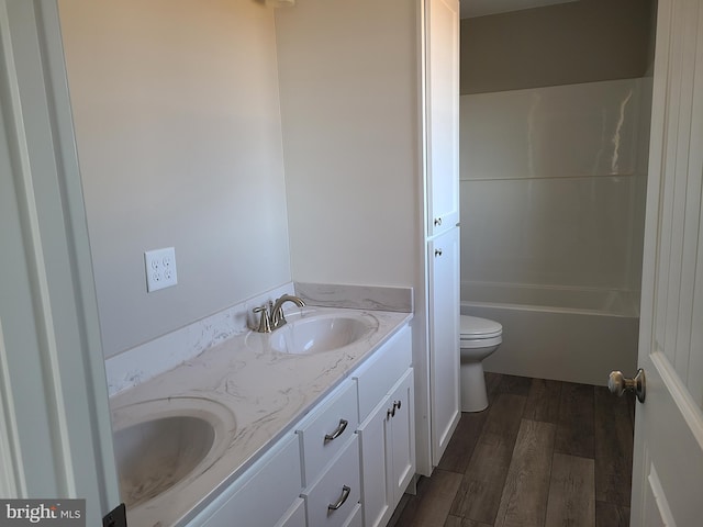 bathroom featuring double vanity, a bathing tub, wood finished floors, and a sink