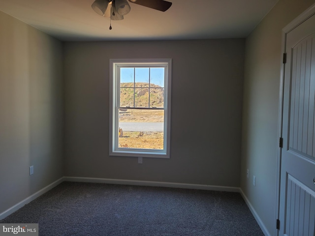 spare room featuring dark carpet, a ceiling fan, and baseboards