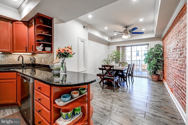 kitchen with dark stone counters, light hardwood / wood-style flooring, sink, dishwasher, and brick wall